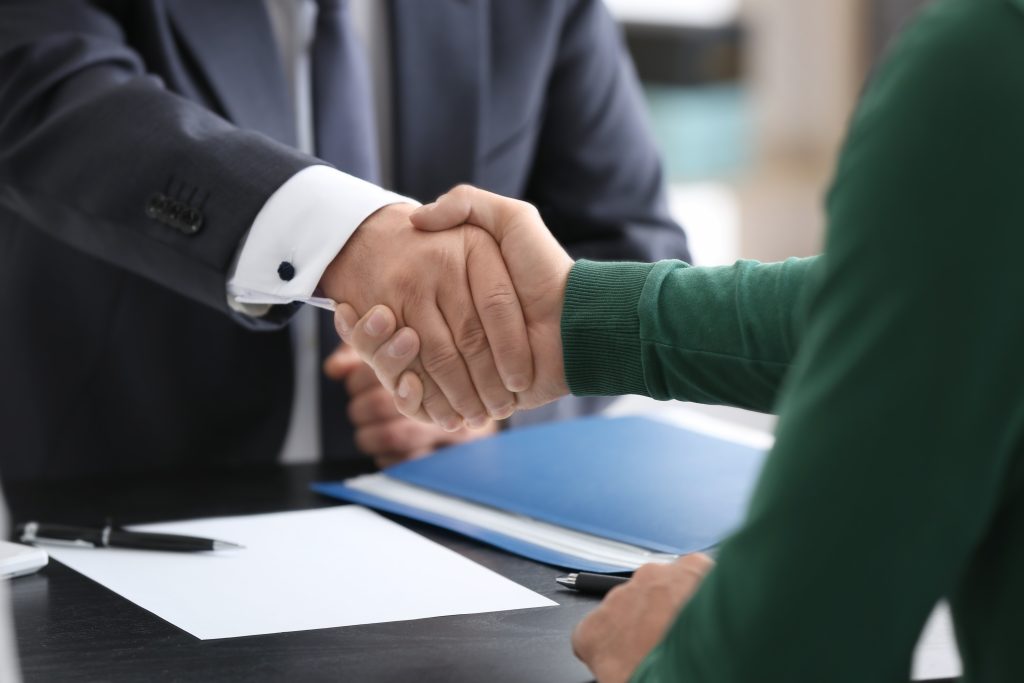 Public Adjuster and client shaking hands in office