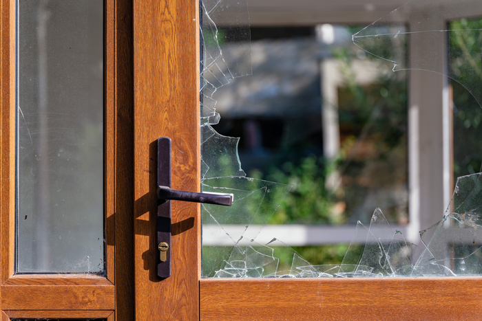 Modern door with handle and broken glass through vendalism